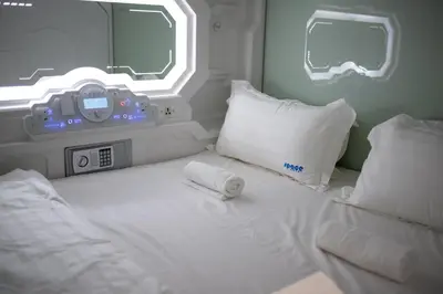 a room with a bed with a clock and a window at Space Hotel KL Sentral in Kuala Lumpur