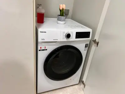 a washer and dryer with flowers on top of it at Sky Suites at KLCC by Mitstay in Kuala Lumpur