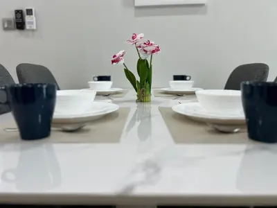 a table with white plates and a vase of flowers at Sky Suites at KLCC by Mitstay in Kuala Lumpur