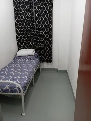 a small room with a chair and a curtain at Sri Rampai Metropolitan Hostel in Kuala Lumpur