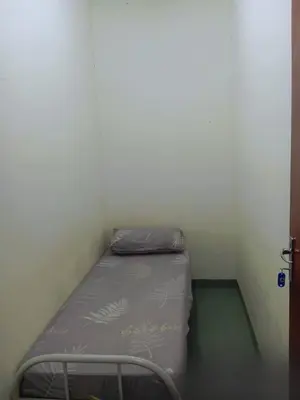 a small bed in a corner of a room at Sri Rampai Metropolitan Hostel in Kuala Lumpur