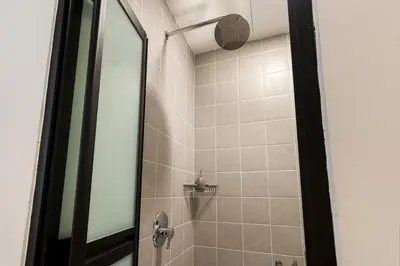a bathroom with a shower with a glass door at Upstairs Downstairs CoLiving Bukit Bintang in Kuala Lumpur