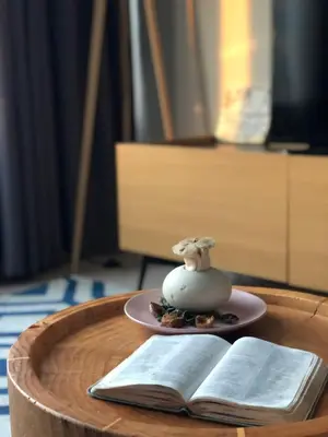 a wooden table with a plate and an open book at Sky Suites KLCC by Psalm Space exclusively for female travellers in Kuala Lumpur