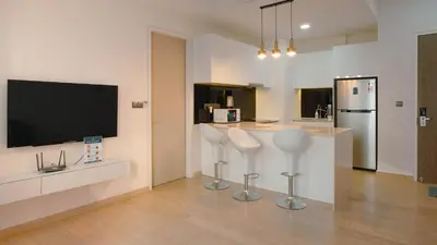 a kitchen with two white stools and a flat screen tv at Star KLCC Twin Tower Suite 2-3pax by DingDing in Kuala Lumpur