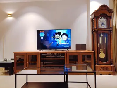 a television on a wooden entertainment center with a clock at Bukit Bintang Pavilion KLCC Wisma Cosway in Kuala Lumpur