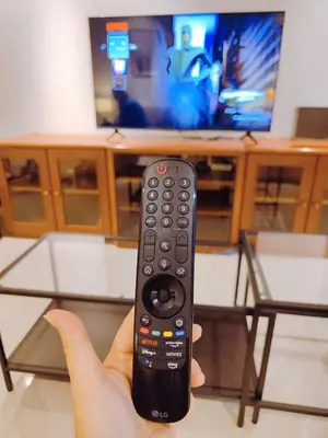a hand holding a remote control in front of a television at Bukit Bintang Pavilion KLCC Wisma Cosway in Kuala Lumpur