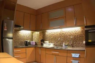 a kitchen with wooden cabinets and a stainless steel refrigerator at Bukit Bintang Pavilion KLCC Wisma Cosway in Kuala Lumpur