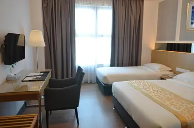 a hotel room with two beds and a desk at Hotel Transit Kuala Lumpur in Kuala Lumpur
