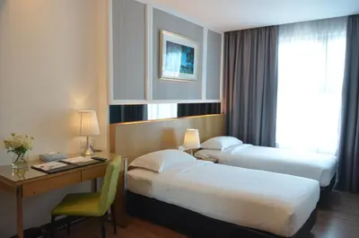 a hotel room with two beds and a desk at Hotel Transit Kuala Lumpur in Kuala Lumpur