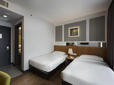 a hotel room with two beds and a table at Hotel Transit Kuala Lumpur in Kuala Lumpur