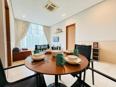 a dining room with a table and a living room at Soho Suites KLCC by DeUrban in Kuala Lumpur