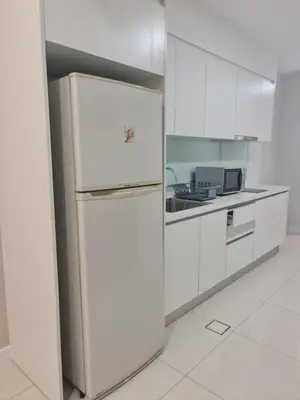 a refrigerator in a kitchen with white cabinets at Muji Themed Apartment by Zen Sojourn - Opposite KL SENTRAL in Kuala Lumpur