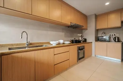 a kitchen with wooden cabinets and a sink at Fahrenheit 88 Pavillion Bukit Bintang 3 bedroom in Kuala Lumpur