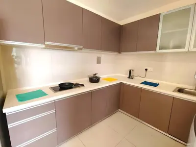 a kitchen with brown cabinets and a counter top at Regalia Residence by Luvit Stay in Kuala Lumpur
