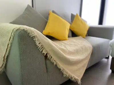 a couch with a blanket on it with yellow pillows at EST Bangsar KL Sentral by DeUrban in Kuala Lumpur