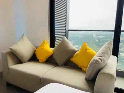 a couch with yellow pillows in a room with a window at EST Bangsar KL Sentral by DeUrban in Kuala Lumpur