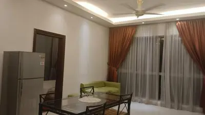 a living room with a table and a refrigerator at Regalia Suite 12-13 in Kuala Lumpur
