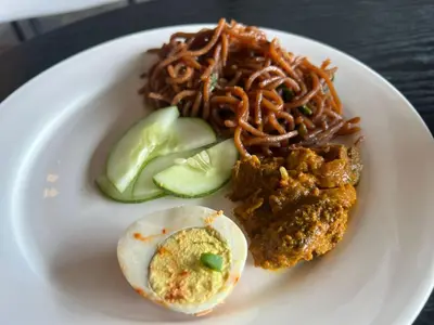 a plate of food with noodles and an egg and avocado at Kingston Hotel 4 - Hulo Bukit Bintang in Kuala Lumpur