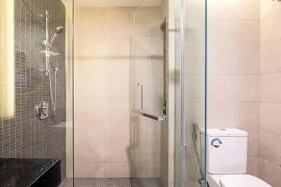 a bathroom with a toilet and a glass shower at Societe Studio Sri Hartamas By Feel Home in Kuala Lumpur