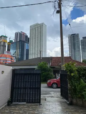 a red car parked in a parking lot with tall buildings at Miharja Studio Private room with Auto gate Parking in Kuala Lumpur