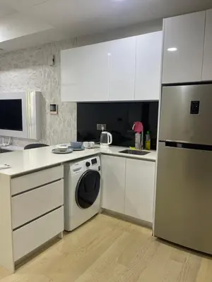 a kitchen with white cabinets and a washer and dryer at Star Residences One in Kuala Lumpur