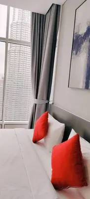 a bed with two red pillows and a window at Sky Suites KLCC by KD Luxury Suites in Kuala Lumpur