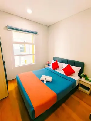 a bedroom with a blue bed with red and orange pillows at Sky Suites KLCC by KD Luxury Suites in Kuala Lumpur