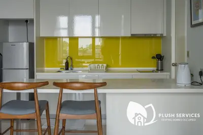 a kitchen with two stools and a counter with yellow at The Signature Serviced Apartment at Sri Hartamas in Kuala Lumpur