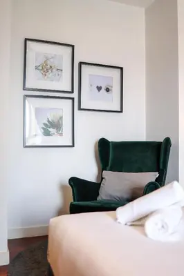 a bedroom with a green chair and pictures on the wall at The Mews KLCC by GB in Kuala Lumpur