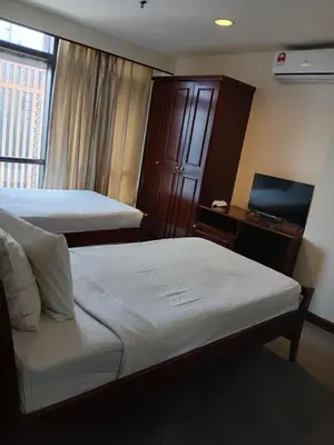 a bedroom with two beds and a desk with a window at Gorgeous service suite at Imbi in Kuala Lumpur