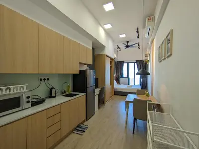 a kitchen with wooden cabinets and a living room at The Luxe KLCC by NZ in Kuala Lumpur