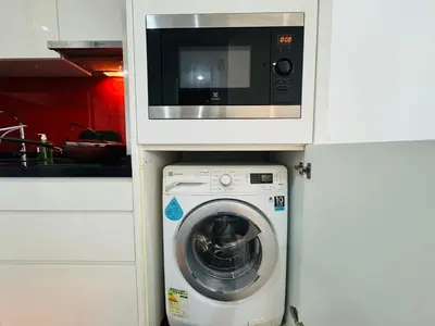 a microwave above a washing machine in a kitchen at Arcoris Residence Mont Kiara by DeUrban in Kuala Lumpur