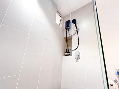 a shower in a bathroom with white tiles at Una Serviced Apartment by Manhattan Group in Kuala Lumpur