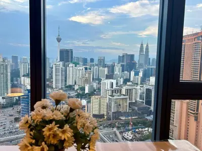 a vase of flowers sitting on a table in front of a window at Studio with Amazing KLCC View & Infinity Pool at Lalaport Bukit Bintang in Kuala Lumpur