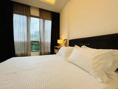 a bedroom with a large white bed with a large window at Dorsett Sri Hartamas by DeUrban in Kuala Lumpur