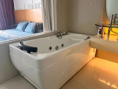 a white bath tub in a bathroom with a window at Private Cinema and Jacuzzi at Pertama Residency in Kuala Lumpur