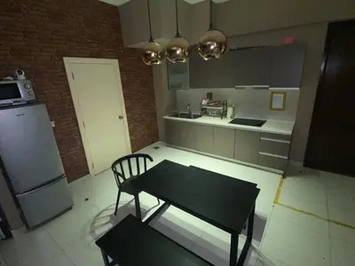 a kitchen with a table and a chair and a refrigerator at Infinity Pool Hostel in Kuala Lumpur