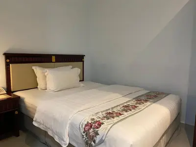 a bedroom with a white bed with a flower blanket at Hotel AL Amin By Ahmed in Kuala Lumpur