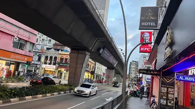 a white car driving down a city street with buildings at Hotel AL Amin By Ahmed in Kuala Lumpur