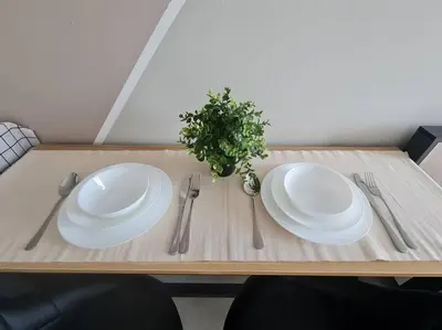 a wooden table with two white plates and silverware at Neu Suites Studio 10mins to KLCC in Kuala Lumpur