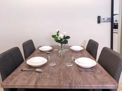 a wooden table with plates and glasses and a vase of flowers at Sky Suite KLCC in Kuala Lumpur