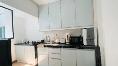 a kitchen with white cabinets and a black counter top at Inara Homestay in Kuala Lumpur