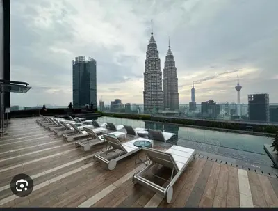 a rooftop pool with lounge chairs and a view of the city at Family comfy 2BR at Star residence2 KLCC in Kuala Lumpur