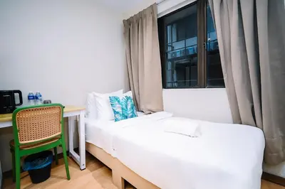 a room with a bed and a desk and a window at Swing & Pillows - Times Square, Bukit Bintang in Kuala Lumpur