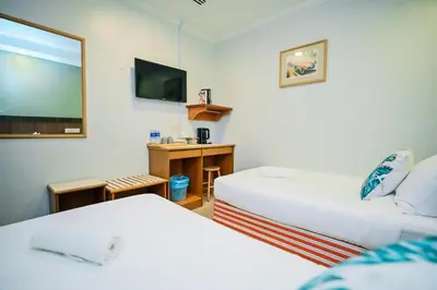 a hotel room with two beds and a flat screen tv at Swing & Pillows - Petaling Street Kuala Lumpur in Kuala Lumpur