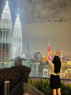 a woman standing on top of a building looking at a city at Star KLCC by homestay in Kuala Lumpur