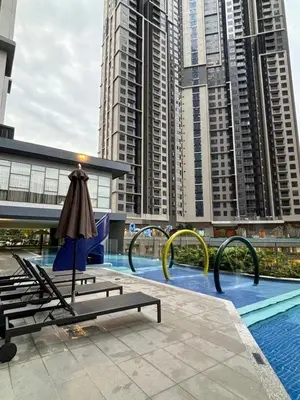 a pool with chairs and an umbrella and some tall buildings at Modern Luxury Apartment, Sunway, TRX in Kuala Lumpur