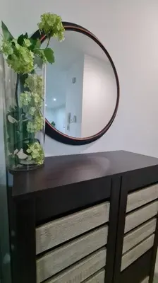 a mirror on top of a dresser with a vase with flowers at Cozy studio family lake view SETAPAK CENTRAL MALL in Kuala Lumpur