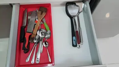 a red container filled with utensils in a drawer at Hostel At Regalia Residence in Kuala Lumpur