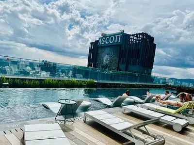 a pool with people sitting on lounge chairs in front of a building at Star Residence KLCC By Starlight in Kuala Lumpur